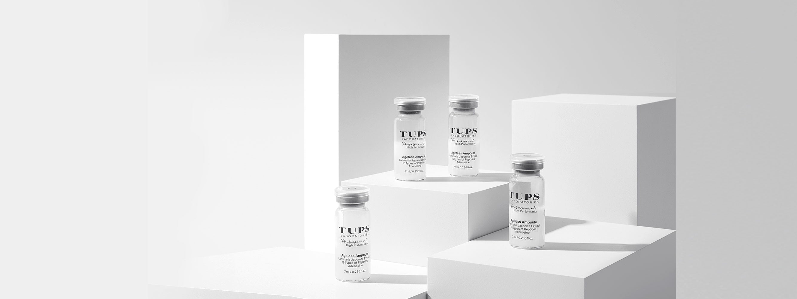 TUPS promotional image with Ageless Ampoules displayed on stands, on a white background with minimal shadow.